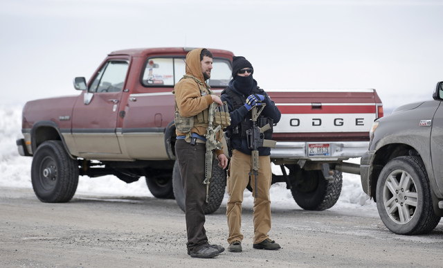 In this Jan. 9, 2016 file photo, men stand guard after members of the "3% of Idaho" group and several other organizations arrived at the Malheur National Wildlife Refuge, near Burns, Ore. (Rick Bo ...