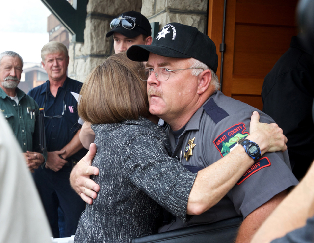 In this Aug. 19, 2015 file photo, Oregon Gov. Kate Brown hugs Grant County Sheriff Glenn Palmer as they enter a meeting with homeowners in Canyon City, Ore. (Thomas Boyd /The Oregonian via AP, File)