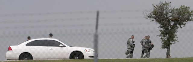 U.S. Air Force personnel gather near the scene of a shooting at Joint Base San Antonio-Lackland, Friday, April 8, 2016, in Texas. (John Davenport/The San Antonio Express-News via AP)