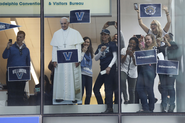 Fans cheer alongside a cutout of Pope Francis as members of the Villanova basketball team have a parade celebrating their NCAA college basketball championship, Friday, April 8, 2016, in Philadelph ...