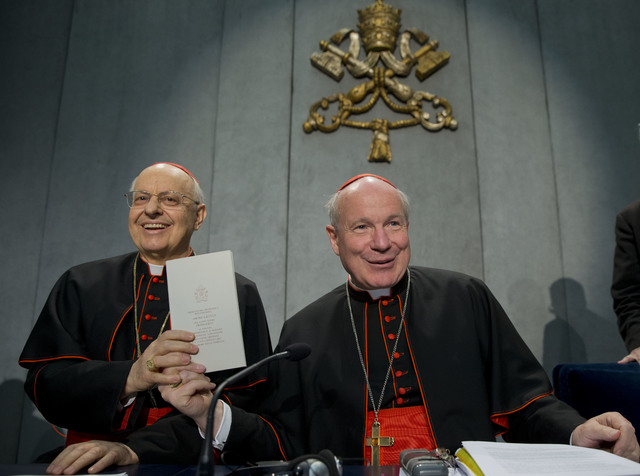 Cardinals Lorenzo Baldisseri, left, and Christoph Schoenborn show a copy of the post-synodal apostolic exhortation ' Amoris Laetitia ' (The Joy of Love) during a press conference at the Vatican, F ...