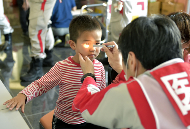 A boy receives medical checkup at a shelter in Mashiki, Kumamoto prefecture, Japan Sunday, April 17, 2016. After two nights of earthquakes, flattened houses and triggered major landslides in south ...