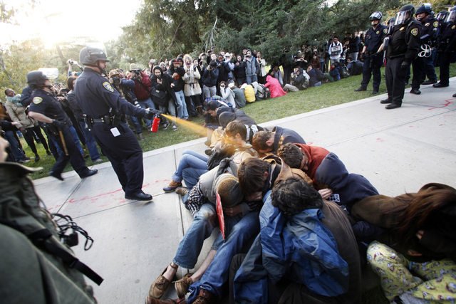 FILE - In this Nov. 18, 2011 file photo, University of California, Davis Police Lt. John Pike uses pepper spray to move Occupy UC Davis protesters while blocking their exit from the school's quad  ...