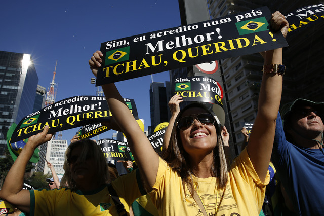 Demonstrators hold signs that reads in Portuguese "Yes I believe in a better country! Goodbye dear," during a protest demanding the impeachment of Brazil's President Dilma Rousseff in Sao Paulo, B ...