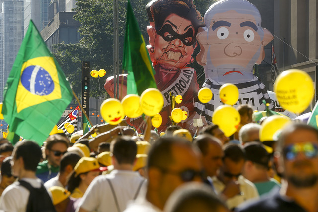 Demonstrators demand the impeachment of Brazil's President Dilma Rousseff during a march next ti large inflatable dolls of former President Luiz Inacio Lula da Silva in prison garb and President R ...
