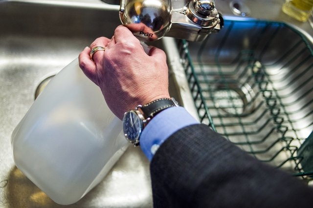 Michigan Gov. Rick Snyder fills empty jugs with filtered Flint, Mich., tap water at Cheryl Hill's house Monday, April 18, 2016, on the city's east side. Gov. Snyder says he will drink Flint's wate ...