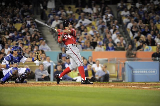 Washington Nationals' Bryce Harper hits a double as Los Angeles Dodgers catcher A.J. Ellis looks on during the seventh inning of their baseball game against the Los Angeles Dodgers, Saturday, Apri ...