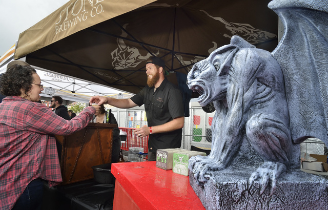 Adam Quinn, center, hands a beer sample to a festival goer at the Stone Brewing company tent during the Great Vegas Festival of Beer in the 800 block of Fremont Street in Las Vegas on Saturday, Ap ...