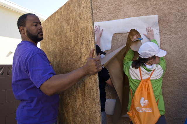 New Genesis Tranditional Housing executive director Maurice Page holds a board to block the wind during a volunteer event held by the Gaels Give Hope organization from Bishop Gorman High School, b ...