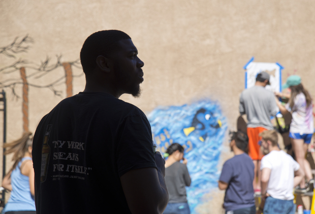 Brandon Russell, a resident at the New Genesis Transitional Housing apartment complex, watches as the Gaels Give Hope organization from Bishop Gorman High School paints murals during a volunteer e ...