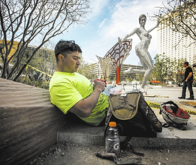 Construction worker Steve Gonzales takes lunch break near the Bliss Dance sculpture created by  Marco Cochrane during an unveiling at The Park, MGM Resorts Internationalճ outdoor dining and  ...