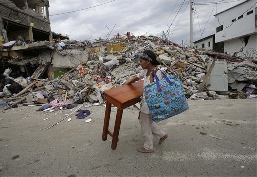 A woman carries a table through the street after an earthquake in Pedernales, Ecuador, Sunday, April 17, 2016. Rescuers pulled survivors from the rubble Sunday after the strongest earthquake to hi ...
