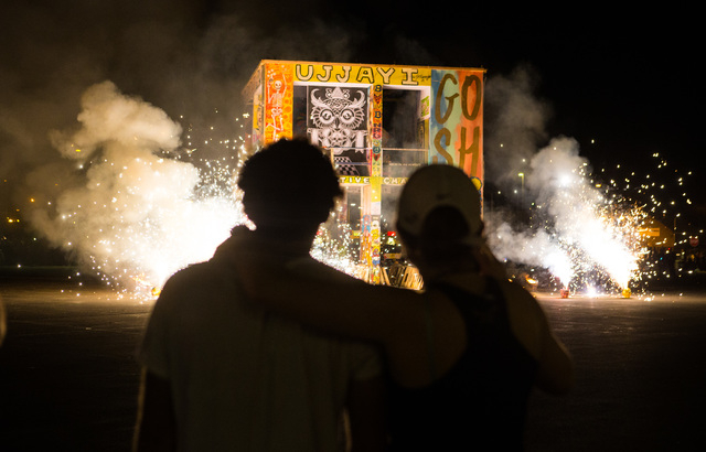 Artist Scott Cohen, creator of the Life Cube Project, left, with daughter Natasha, watches as the fire ceremony goes on for the Life Cube in downtown Las Vegas on Saturday, April 2, 2016. (Chase S ...