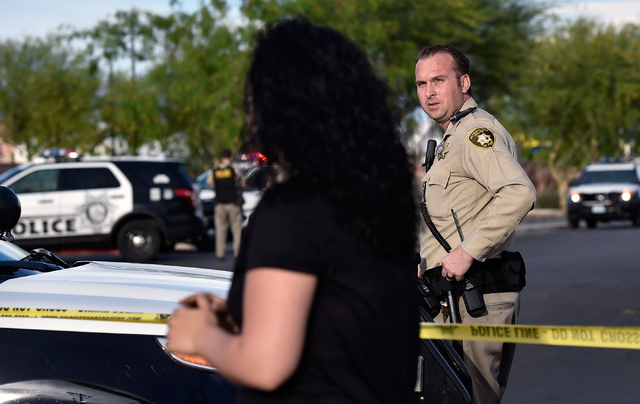 A neighbor is stopped by police as she tries to enter her apartment complex along Cecile Avenue Friday, April 8, 2016, in Las Vegas. Police have blocked off access in and around the North East Are ...