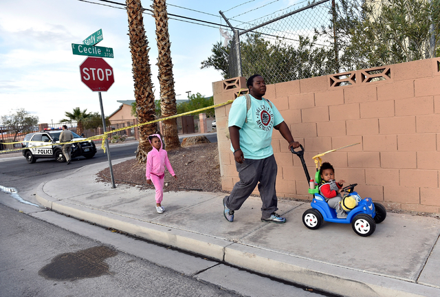 A man with his children are rerouted as they are stopped by police tape trying to enter their apartment complex along Cecile Avenue Friday, April 8, 2016, in Las Vegas. Police have blocked off acc ...