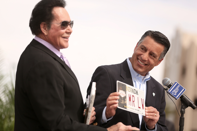 Nevada Gov. Brian Sandoval gives entertainer Wayne Newton a vanity plate during the Project Neon groundbreaking in Las Vegas on Thursday, April 7, 2016.  The $1.5 billion project will add traffic  ...