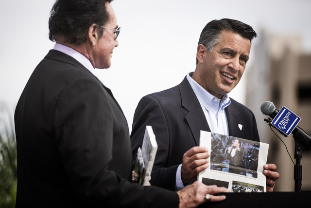 Nevada Gov. Brian Sandoval, right, holds a copy of the Review-Journal showing a photo of entertainer Wayne Newton  while honoring him during the groundbreaking for Project Neon near The Smith Cent ...