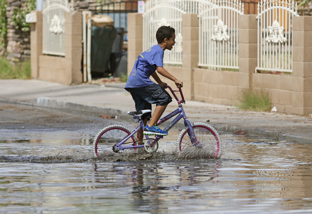 A child rides a bike through a flooded area of Valley View Boulevard near San Angelo Avenue Saturday, April 9, 2016, in Las Vegas. (Ronda Churchill/Las Vegas Review-Journal)