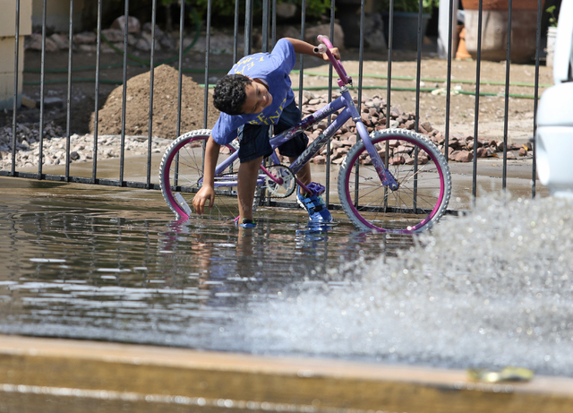 A child waits to be splashed by cars driving along a flooded area of Valley View Boulevard near San Angelo Avenue Saturday, April 9, 2016, in Las Vegas. (Ronda Churchill/Las Vegas Review-Journal)