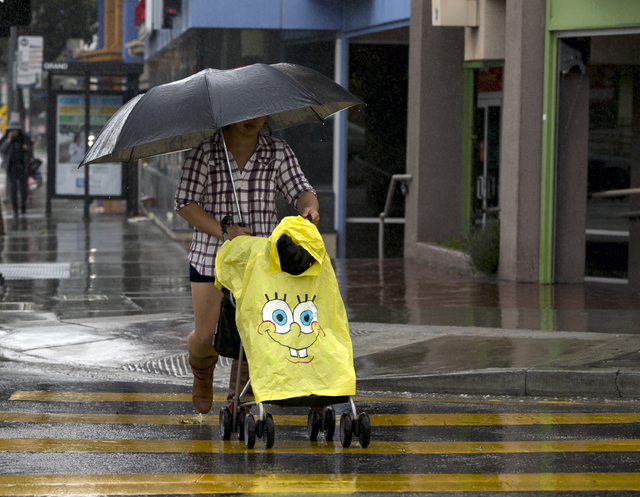 A pedestrian walks in the rain in downtown Los Angeles on Friday, April 8, 2016. (Damian Dovarganes/The Associated Press)