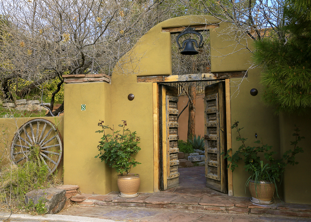 A Santa Fe architect incorporated wood artifacts from Santa Fe, such as corbels, a mission bell and wagon wheels in the yard. The door at the base of the sidewalk was imported from Indonesia. (ELK ...