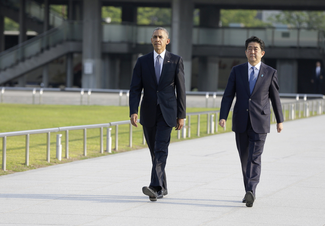 U.S. President Barack Obam, left, walks with Japanese Prime Minister Shinzo Abe for a wreath-laying ceremony at Hiroshima Peace Memorial Park in Hiroshima, western, Japan, Friday, May 27, 2016. Ob ...