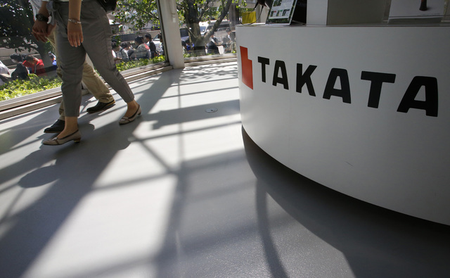 In this May 4, 2016 file photo, visitors walk by a Takata Corp. desk at an automaker's showroom in Tokyo.  Eight automakers are recalling more than 12 million vehicles in the U.S. to replace Takat ...