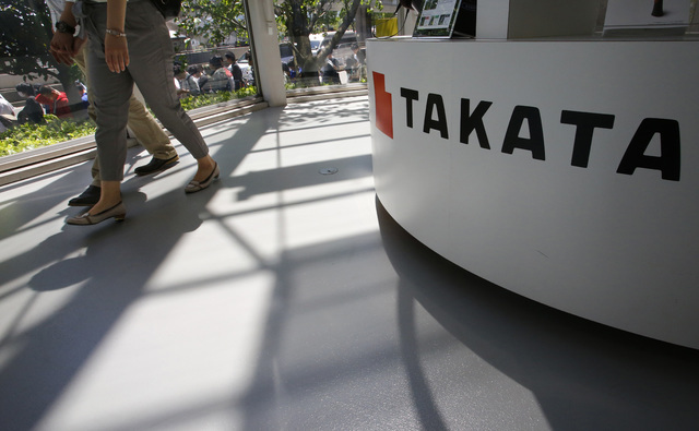 In this May 4, 2016 file photo, visitors walk by a Takata Corp. desk at an automaker's showroom in Tokyo. Eight automakers are recalling more than 12 million vehicles in the U.S. to replace Takat ...