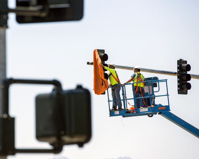 A work crew removes the cover from the first traffic light in Baker, Cal. on Monday, May, 23, 2016. The owner of Baker Travel Plaza spent four years trying to install the signal because it is chea ...