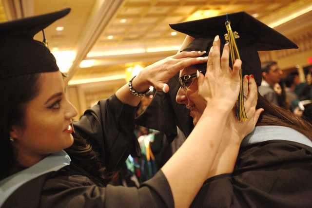 Touro University Nevada graduate Yischelli Martinez adjusts the cap of fellow graduate Maggie Marschner as they wait in a ballroom for their graduation ceremony at the Rio Hotel and Casino Sunday, ...