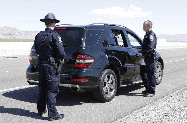 Nevada Highway Patrol trooper Jeff Freeman talks to a driver who was pulled over for failing to move over for stopped patrol car on I-15 North in Jean as trooper Jason Buratczuk, left, looks on Fr ...
