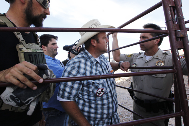 Dave Bundy, middle, talks with Las Vegas Metro Police Chief Deputy Tom Roberts, right, while trying to convince the BLM to release their impounded cattle outside of Bunkerville on April 12, 2014.  ...