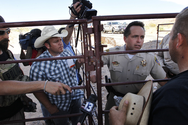 Dave Bundy, left, and his brother Ammon Bundy, far right, talk with Las Vegas Metro Police Chief Deputy Tom Roberts while trying to convince the BLM to release their impounded cattle outside of Bu ...