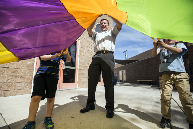 The Rev. Michael Engfer plays a parachute game with students at All Saints Episcopal Church, 4201 W. Washington Ave. Engfer, serves both All Saints Episcopal Church and the Air Force Reserves as a ...