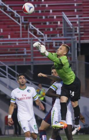 New York Cosmos goalie Brian Holt (24) punches a ball out of the box while defender Sebastian Guenzatti (13) looks on during a friendly between the New York Cosmos and SD Eibar, Wednesday, May 25, ...