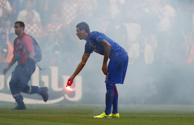 A flare is thrown onto the pitch by fans and is picked up by Croatia's Mario Mandzukic during the Euro 2016 Group D soccer match between the Czech Republic and Croatia at the Geoffroy Guichard sta ...