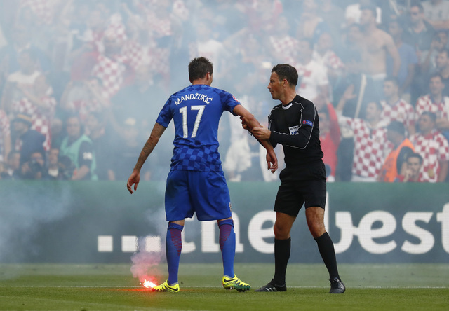 A flare is thrown onto the pitch by fans as Croatia's Mario Mandzukic speaks with referee Mark Clattenburg during the Euro 2016 Group D soccer match between the Czech Republic and Croatia at the G ...