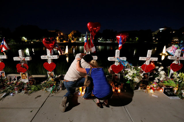 Jose Louis Morales cries on his knees as he is hugged by a woman at his brother Edward Sotomayor Jr.'s cross, that is part of a makeshift memorial for the victims of the Pulse night club shootings ...