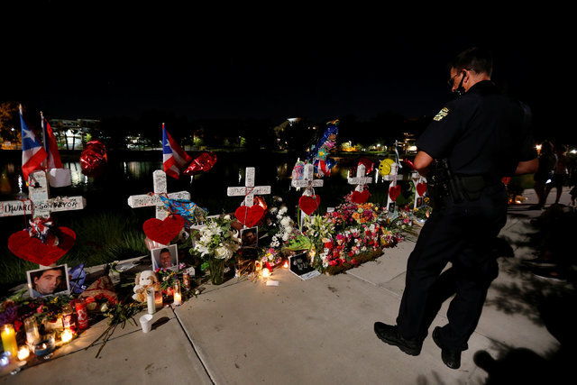A police officer looks at a row of crosses that make up part of a makeshift memorial for the victims of the Pulse night club shootings in Orlando, Florida, U.S., June 20, 2016.  REUTERS/Carlo Allegri