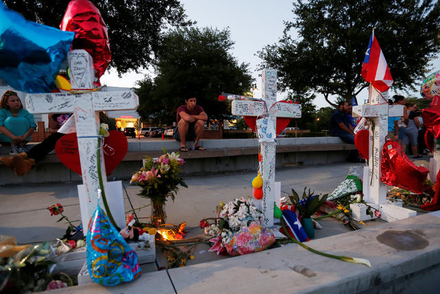 A man sits and looks at a row of crosses that make up part of a makeshift memorial for the victims of the Pulse night club shootings in Orlando, Florida, U.S., June 20, 2016.  REUTERS/Carlo Allegri