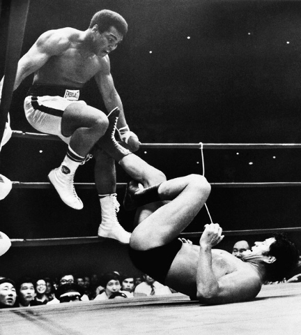 FILE - In this July 26, 1976, file photo, world heavyweight boxing champion Muhammad Ali is shown trying to evade kicks by wrestler Antonio Inoki during their 15-round World Martial Arts match, in ...