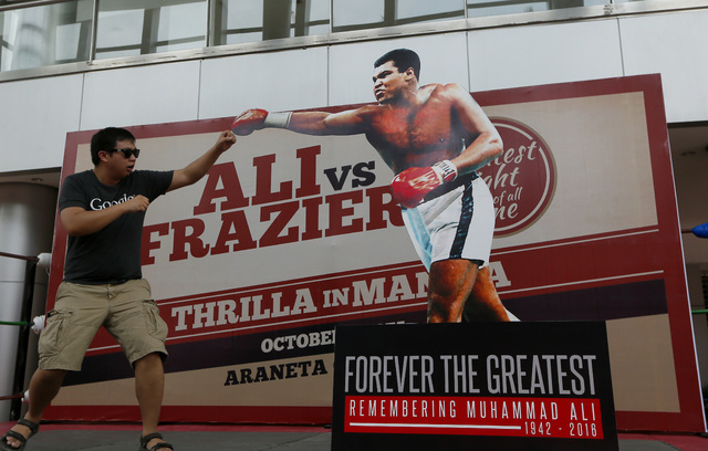 Romy Doria poses before a standee of Muhammad Ali during the