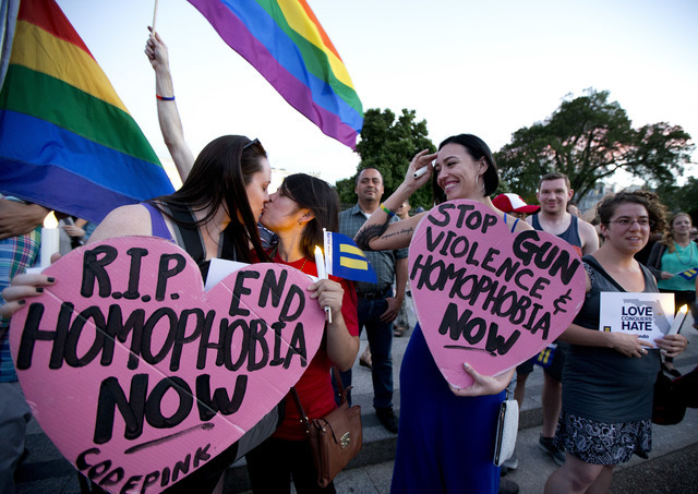 Rachel Henry, left, and Selene Arciga, kiss to show their solidarity with members and supporters of the LGBT gathered for a candlelight vigil in front of the White House in Washington, Sunday, Jun ...