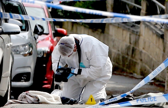 A forensics officer takes photos of a female shoe at the scene after Labour MP Jo Cox was killed being shot and stabbed in an attack in her constituency, in Birstall, West Yorkshire, England, Thur ...