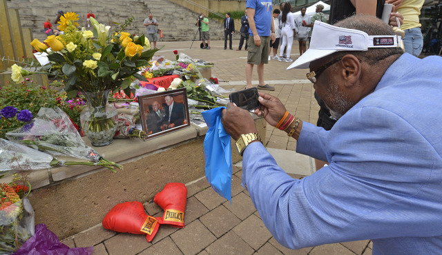 Frank Green, of Louisville, Ky., takes a photograph of a memorial for Muhammad Ali at the Muhammad Ali Center, Saturday, June 4, 2016 in Louisville, Ky. (Timothy D. Easley/The Associated Press)