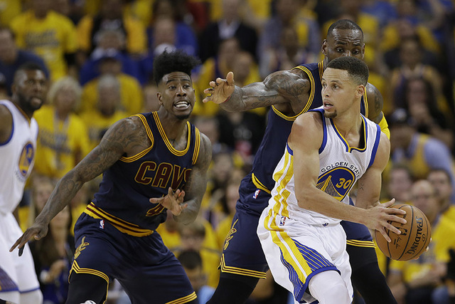Golden State Warriors guard Stephen Curry (30) is guarded by Cleveland Cavaliers forward LeBron James and guard Iman Shumpert (4) during the second half of Game 1 of basketball's NBA Finals in Oak ...