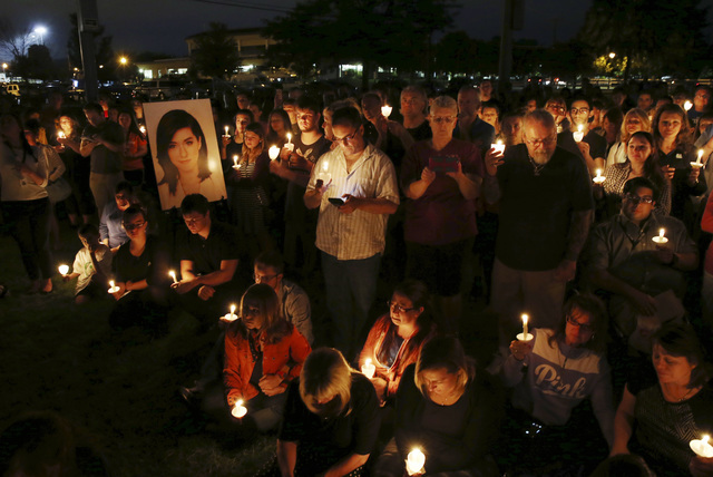 People stand near a large photograph as they hold candles during a vigil to honor Christina Grimmie, the singer who was fatally shot last week after a concert in Florida, June 13, 2016, in Evesham ...