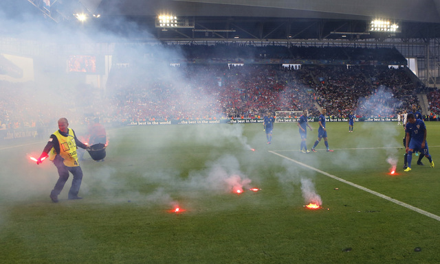 Flares are thrown onto the pitch during the Euro 2016 Group D soccer match between the Czech Republic and Croatia at the Geoffroy Guichard stadium in Saint-Etienne, France, Friday, June 17, 2016.  ...