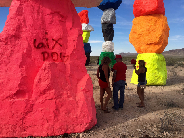 People stand in the shade of the towering rocks at the Seven Magic Mountains art project off Interstate 15 on Sunday, June 5, 2016.  (Natalie Bruzda/Las Vegas Review-Journal)