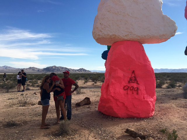 People stand in the shade of the towering rocks at the Seven Magic Mountains art project off Interstate 15 on Sunday, June 5, 2016. (Natalie Bruzda/Las Vegas Review-Journal)